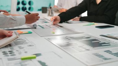 Çağdaş bir ofis ortamında takım çalışmasını gösteren çeşitli profesyoneller, veri tabloları ve istatistiklerin analiz edilmesi üzerinde çalışmaktaydı. SACTR