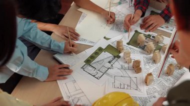 Mimari belge, ölçüm aracı ve ahşap blokların modern ofiste etrafa saçıldığı bir masa üzerinde yapı inşaatı ile ilgili mimar ve güvenlik mühendisi tartışması. Tanımlama.