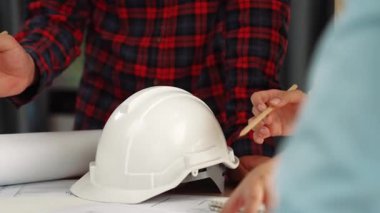 Mimarlık ve güvenlik mühendisi, modern ofiste dizüstü bilgisayarda mimari belge ve ahşap blokla sergilenen planlar hakkında tartıştı. - Yakın çekim. Tanımlama.