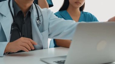 Hastane masasında birlikte çalışan ve tıbbi tedavi planlayan çeşitli profesyonel sağlık görevlileri. Takım çalışması başarılı hastalıklara ve hastalıklara yol açar. Ağır çekim. Katı.