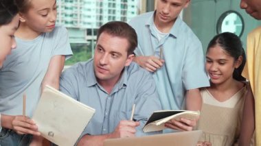 Akıllı robotlar sınıfta dizüstü bilgisayar ekranını işaret ederken, beyaz bir öğretmen yorum yapıyor ya da öğrencilere tavsiye veriyor. Öğretmen bilgisayar kullanırken çeşitli öğrencilerin ders verirken not alması. Öğretim