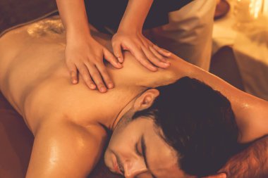 Beyaz erkek müşteri stres önleyici spa masajının keyfini çıkarıyor ve lüks otel ya da oteldeki ortam kaplıcalarında sıcak mum ışığında güzellik teniyle eğleniyor. Sessiz.
