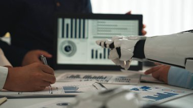 Dinamik bir iş toplantısında modern bir ofiste profesyonellerle ilişki kuran bir robot asistan ayrıntılı veri analizi ve etkili raporlar sunuyor.