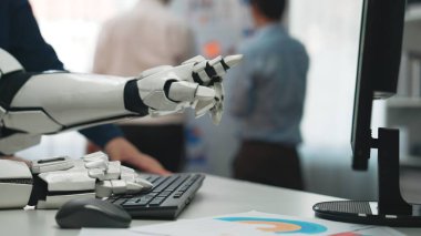 Bilgisayar klavyesiyle etkileşime giren robotik bir kolun yakın plan çekimi, iş ortamında modern teknolojiyi sergilemek, profesyonellerin arka planda işbirliği yapması.Noogenesis