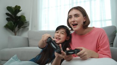 Kafkas anne ve kızı oturma odasında oturup oyun oynuyorlar. Mutlu anne, elinde joystick tutarken akıllı Asyalı kızla vakit geçiriyor. Oyun oynamaktan zevk alıyor. Yaşam tarzı konsepti. Pedagoji.