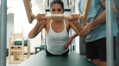 Pilates Cadillac masasında bar tabanlı bir alıştırmada bir müşteriye yardım eden eğitmen. Cadillac 'ta kuğu dalışı yapan kadın beden gücünü ve beden eğitimini arttırıyor. Alışkanlık.