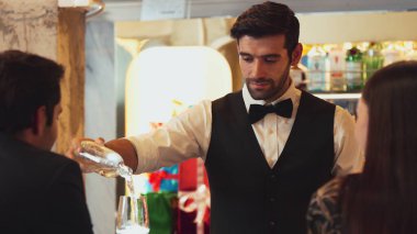 Zeki, gülümseyen barmen lüks bir barda buzlu içecekler hazırlarken aynı zamanda canlı, aydınlık atmosfer barında ve restoranda VIP müşterilerle canlı sohbetler yapıyor. Vinosity.