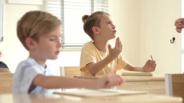 Beyaz bir çocuk ödevlerini yaparken ve açıklama dinlerken güzel bir öğretmen sınavı açıklıyor. Sınıfta not alırken ya da kağıda cevap yazarken öğretmenine bakan sevimli bir çocuk. Pedagoji.