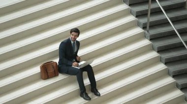 Merdivenlerde dizüstü bilgisayar kullanarak yatırımcıların çalışma ya da planlama stratejisinin en üst görüntüsü. Modern bir otelde dizüstü bilgisayar kullanarak veri analizi yapan takım elbiseli profesyonel bir iş adamı. Sevinçli..