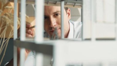 Kafkasyalı mimar mühendisinin yakın çekimi ev inşaatını denetlemek ve bina malzemelerini kontrol etmek. Proje yöneticisi modele dikkatlice bakarken kalemi işaret ediyor. Yönlendirici.