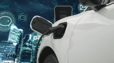 5G Network dijital hologramı ve internet tabelaları gece şehrinin arka planında beliriyor. Çevre koruma kavramı için kablo prizi olan şarj istasyonuna bağlı ilerici elektrikli araç.
