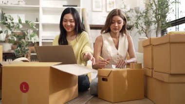 Çekici bir oda arkadaşı oturma odasında paket paketlerken pakette konum yazıyor. Mutlu satıcı birlikte çalışıyor ve teslimat paketini hazırlıyor. Girişimci kargo kutusu paketliyor. Myrmidon.