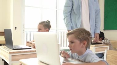 Kafkasyalı öğretmen Amerikan öğrenci kodlama mühendisliğine yardım ederken çeşitli öğrenciler yapay zeka yazılımı kullanıyor. Akıllı çekici çocuklar oturuyor ve programlıyor. Eğitim. Pedagoji.