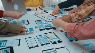 Çeşitli bir ekip, modern bir çalışma alanında dijital modeller ve dizüstü bilgisayarlar kullanarak kullanıcı arayüzü tasarımı üzerinde işbirliği yapar. Yaratıcılık ve takım çalışması yenilikçi fikirlere ilham verir. SACTR