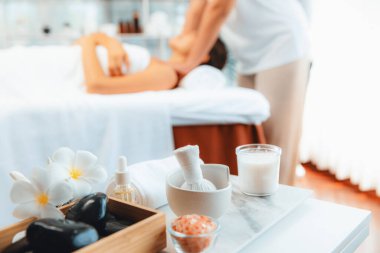 Aromaterapi masajı gündüz atmosferinde ya da spa salonunda bulanık bir kadına odak dekor ve spa aksesuarları kurarak tatil köyünde ya da otel arka planında keyifli aroma spa masajı yapan bir masaj. Sessiz.