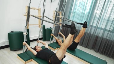 Bir grup müşteri, çekirdek dayanıklılığını ve bacak bağını geliştirmek için Cadillac reformatör makinesinde pilates egzersizleri yapıyor. Sağlıklı müşterilerin daha düşük poz verip kaldırma pozlarının üst görüntüsü. Sağlıklılık. Alışkanlık.