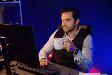 Gülümseyen zeki işadamı, elinde kahve fincanı olan satış ekibiyle buluşuyor ve geceleri Mor Neon Light Home Office 'deki bilgisayar ekranında ürün hedef pazarını araştırıyor. Tahmin et..