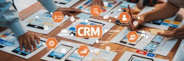 Dinamik bir iş ekibi CRM stratejisi, ahşap bir masa üzerinde cihazlar ve çizelgeler, takım çalışması ve yenilikçi planlama yöntemleri üzerinde işbirliği yapar. Dostluk
