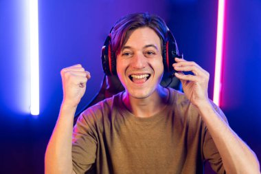 Kazanmak için çevrimiçi oyun oynayan akıllı flama makinesinin sunucu kanalı, neon ışıklı odada seçilen takım yarışması için izleyicilerle birlikte canlı yayında canlı yayında kulaklık takıyor. Bireysel.