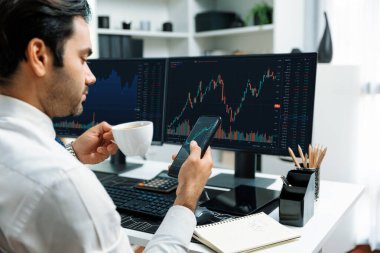 Elinde telefon dinamiğine odaklanan kahve fincanı tutan borsa yatırım ekranı veri analizini karşılaştırarak iç işlerinde yüksek kârlı finans teknolojisi pazarına yatırım yapıyor. Tahmin et..