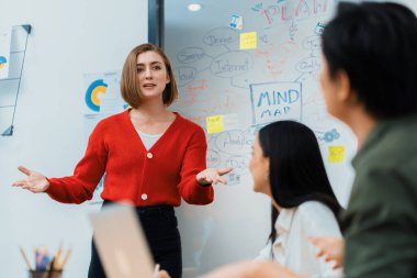 Kafkasyalı genç bir iş kadını, pazarlama stratejisini zihin haritası kullanarak sunuyor, soruları kendinden emin bir şekilde cevaplarken grafiğini çiziyor. Takım çalışması, beyin fırtınası, tartışma konsepti. Tertemiz..
