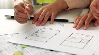 Mimari ekipmanlarla toplantı masasında ev tasarımı üzerine profesyonel mühendis ekibi tartışması ve modern ofiste bina planı dağılımı. Eline odaklan. - Yakın çekim. Tanımlama.