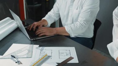 Bir grup mimar mühendis birlikte çalışıyor ve ofis tasarımı hakkında tartışıyorlar. Genç mühendis ev modelini ölçerken yönetici dizüstü bilgisayar kullanıyor. İş tasarımı konsepti. Yönlendirici.