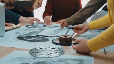 Çeşitli mühendislik ekipleri bir ofis ortamında iş birliği yaparak, mekanik planlar üzerinde çalışır ve yenilikçi proje tasarımlarını rafine etmek için araçlar kullanır. SACTR