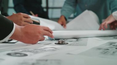 Çeşitli profesyoneller, modern bir ofisin mimari planları ve planlarını inceleyerek, takım çalışması ve yaratıcılığı sergileyerek işbirliği içinde çalışırlar. SACTR