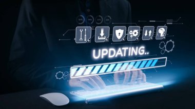 Bu stok fotoğrafı, bir yükleme ilerleme çubuğu ve güncelleme iletisi gösteren holografik bir arayüzle gelecekteki bir klavyeyle etkileşen elleri yakalar. Dörtgen