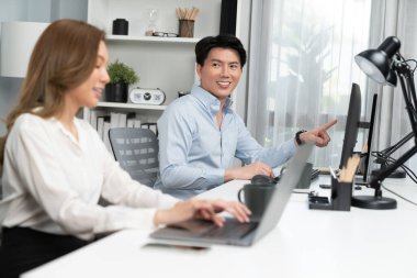 Gülümseyen Asyalı bir adam, yan görüntüdeki modern ofis çalışma masasında veri tabanını ararken günlük dizüstü bilgisayarla pazarlama raporu projesini planlarken kadın meslektaşıyla konuşuyor. İnfobahn.