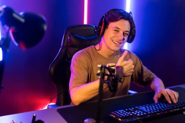 Oyun kanalı, online oyun oynayan akıllı flamalı oyun sunucusu, kulaklık takan, neon ışıklandırma odasındaki takım oyuncusuyla akıllı telefondan canlı yayında konuşan izleyiciler. Bireysel.