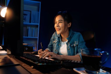 Gülümseyen genç Asyalı yaratıcı memur internette satış hedefine bakıyor. Neon lambası gecesinde yeni strateji pazarlaması planlamak için serbest iş sahibi oluyor. Taktik.