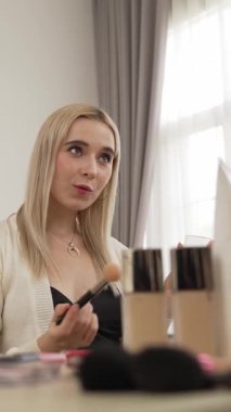 Sosyal medya için güzellik ve kozmetik video içeriği hazırlayan genç bir kadın. Güzellik blogcusu kameraya gülümserken seyircilere ve takipçilere güzellik bakımını gösteriyor. Blithe