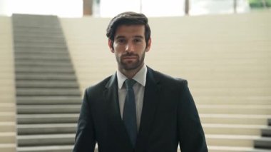 İş adamı kameraya bakarken kollarını kavuşturup arkasını dönüyor. Zeki, yakışıklı proje yöneticisi kameraya poz verirken kendine güvenen, arka planı bulanık bir şekilde merdivenlerde gülümsüyor. Sevinçli..