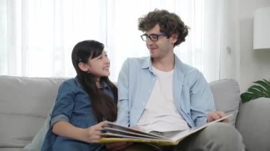 Mutlu kız babaya yaslanır hikaye anlatırken. Genç Asyalı liseli kız birlikte masal kitabı okurken ve kanepede otururken babasını arıyor. Aile eğlence konsepti. Pedagoji.