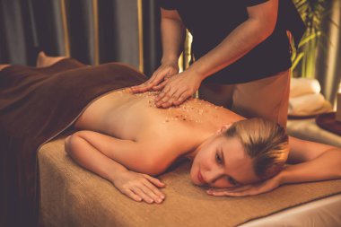 Lüks spa salonlarında sıcak mum ışığında cilt bakımı yaptıran kadın müşteri. Sağlık Spa vücut fırçasında tuz temizleme güzellik tedavisi. Sessiz.