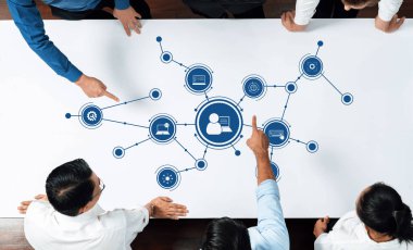 Bir grup iş adamı, veri akışı ve yenilikçi teknoloji kavramlarını sembolize eden bir dijital ağ diyagramını analiz ederek bir masa etrafında işbirliği yapıyor. Dostluk