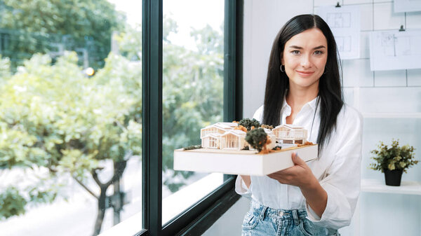 Крупный план квалифицированного молодого красивого кавказского архитектора лифта дом модели левой и правой стороны, чтобы проверить и сосредоточиться на проверке ошибок точки в современном офисе с чертежом. Непорочный.