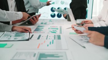 Çeşitli iş adamları bir araya gelerek verileri analiz ediyor ve çeşitli grafik ve grafiklerle raporları tartışıyor. SACTR