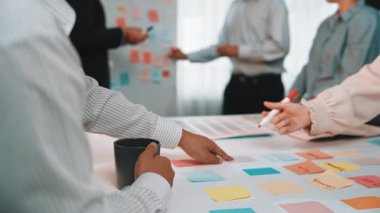 Modern bir ofiste, renkli yapışkan notlarla beyin fırtınası yapan, yaratıcı ve takım çalışmasını ön plana çıkaran farklı bir grubun dinamik bir sahnesi. SACTR