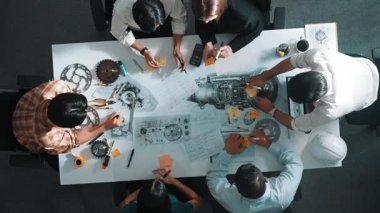 Üstten görünüşlü akıllı mühendis ekibi metal teçhizatlı, hesap makineli, yapışkan notlu türbin motor yapısı hakkında konuşuyor. Bir grup teknisyen toplantıda not alıyor. Hizalama.