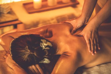 Beyaz kadın müşteri stres önleyici spa masajının keyfini çıkarıyor ve lüks otel ya da otelde sıcak mum ışığında güzellik teniyle eğleniyor. Sessiz.