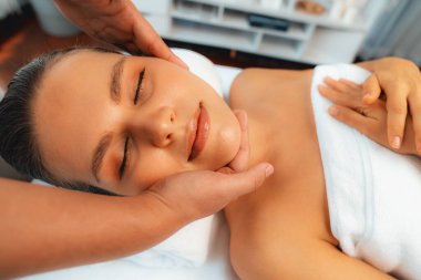 Kafkasyalı kadın stres önleyici kafa masajından ve lüks tatil beldesi ya da otel spa salonundaki modern ışık ortamında yüz güzelliği eğlencelerini şımartmaktan hoşlanıyor. Sessiz.