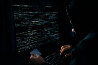 Suçlu anonim erkek, gece vakti mavi neon ışıklı odada sunucu sürücüsü ile şifre kırma programı kodlamak için kişisel bilgi veritabanının kredi kartına yaklaşıyor. Tahmin et..