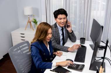 Gülümseyen Asyalı işadamı komisyoncu dinamik borsa veritabanını arıyor. Kadın iş ortağı, iç işyerindeki kar eden uygulama programını karşılaştıran ekranlara işaret ediyor. İnfobahn.