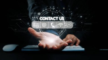 Bir el, dijital iletişim sembolleriyle çevrili, iş ve teknoloji ortamlarındaki bağlantıyı ve desteği temsil eden parıldayan bir iletişim simgesine doğru uzanıyor. Dörtgen