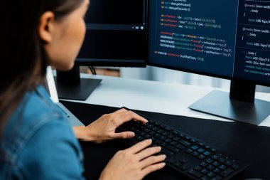 İnternet sitesi uygulamasının kodlama verileriyle birlikte online bilgi yazarak kot gömlek giyen genç Asyalı geliştirici. Güvenlik analizi ile çevrili iki ekran. Taktik.
