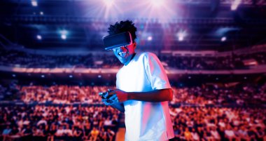 Yetişkinlerin elinde joystickle VR gözlükleri varken stadyumda arka planda bulanık oyunlar oynamaktan zevk alıyorlar. Afrikalı adam kontrol etmeyi ve artırılmış gerçeklik teknolojisini kullanmayı seviyor. Yaratıcılık.