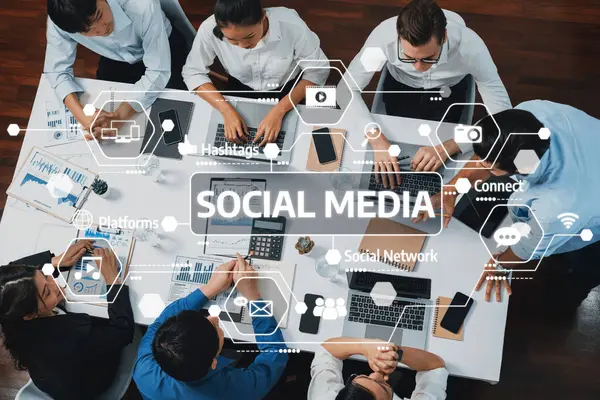 Sosyal medya simgeleriyle çevrili, iş dünyasında takım çalışması ve dijital iletişimin sergilendiği çağdaş bir ofiste çeşitli profesyonellerden oluşan bir grup dizüstü bilgisayar üzerinde işbirliği yapıyor. Dostluk